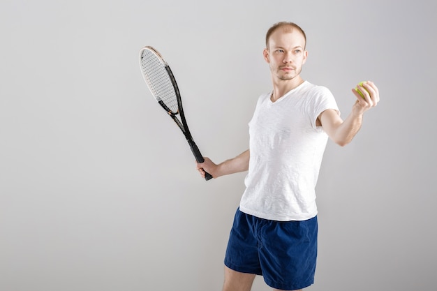 Joven tenista juega al tenis en un gris