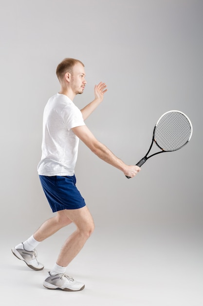 Joven tenista juega al tenis en un gris