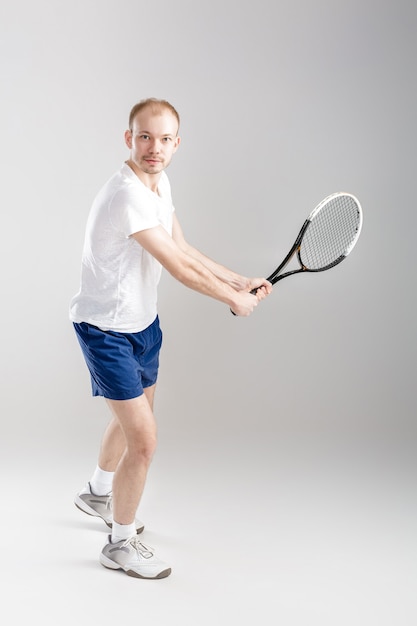 Joven tenista juega al tenis en un gris