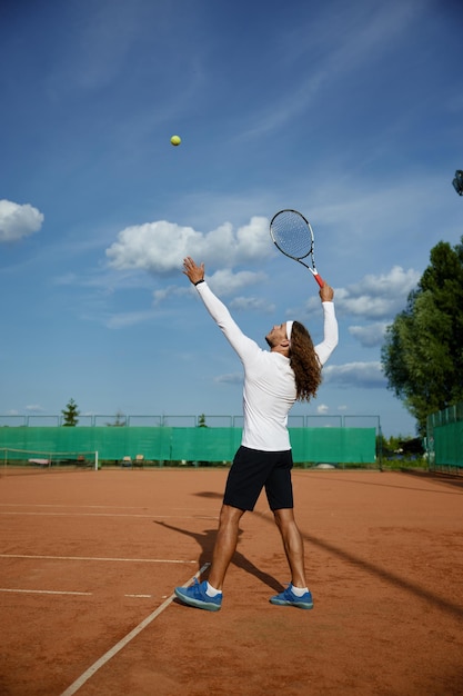 Joven tenista masculino dedicado a entrenar en una cancha de deportes al aire libre