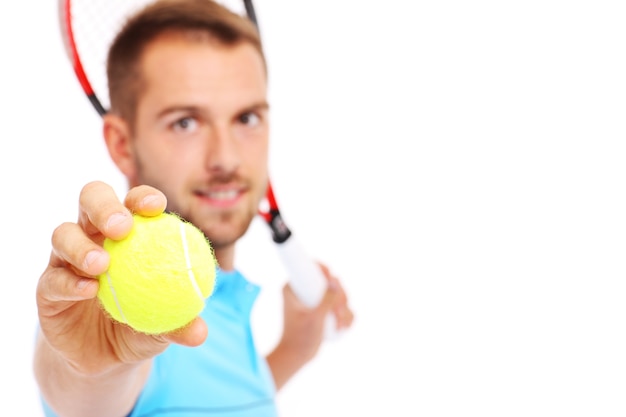 Un joven tenista mostrando una pelota sobre fondo blanco.