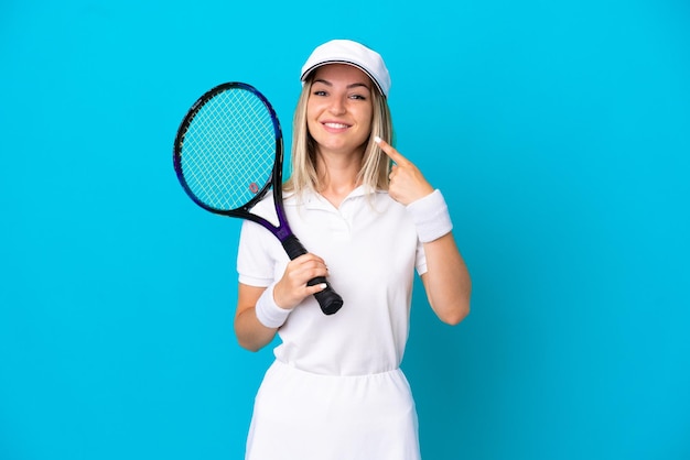 Joven tenista mujer rumana aislada sobre fondo azul dando un pulgar hacia arriba gesto