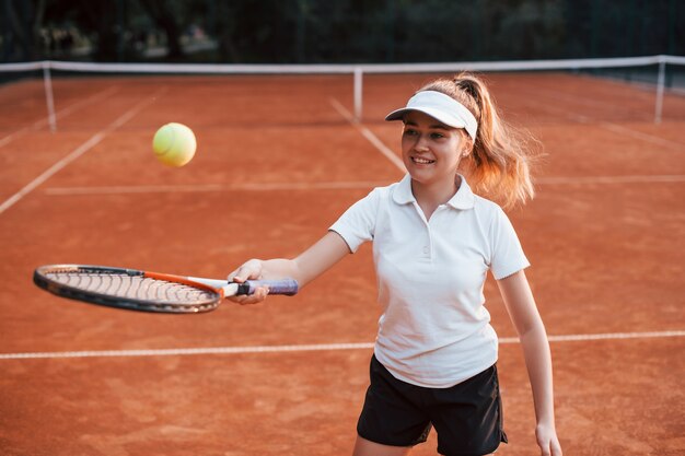 Joven tenista en ropa deportiva está en la cancha al aire libre.