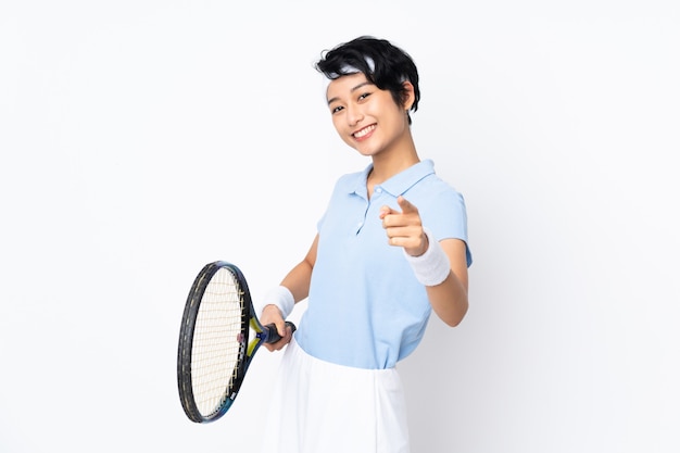 Joven tenista vietnamita mujer sobre pared blanca aislada jugando tenis y apuntando hacia el frente