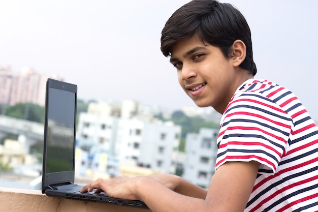 Un joven en la terraza de la casa con el portátil estudiando desde el hogar Concepto de educación en línea