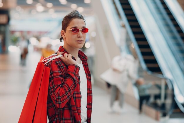 Un joven va a la tienda del centro comercial con bolsas de compras.