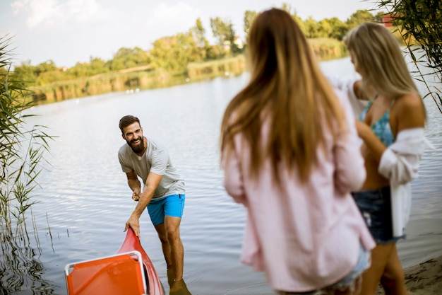 Foto joven tirando de la canoa en el lago tranquilo