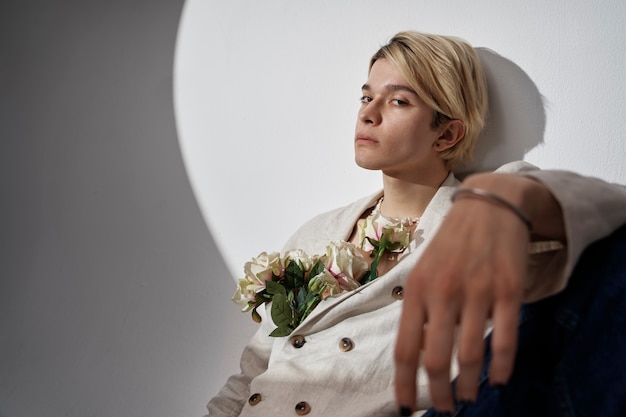 Foto joven de tiro medio posando con flores en el estudio