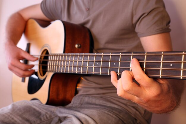 Joven tocando la guitarra acústica de cerca