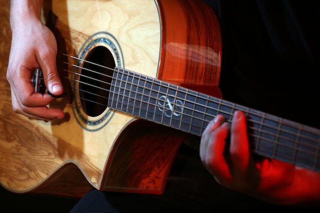 Joven tocando la guitarra acústica de cerca