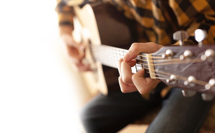 Un joven tocando la guitarra acústica. Vista cercana. Diseño de plantillas.