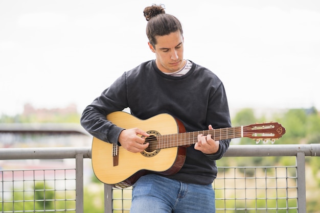 Joven tocando la guitarra española en el campo