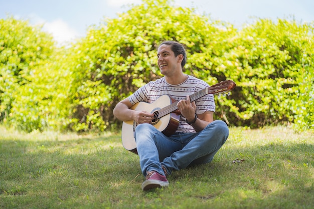 Joven tocando la guitarra española en el campo