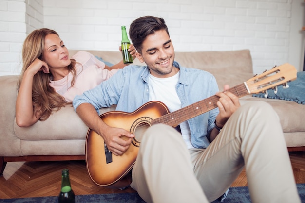 Joven tocando la guitarra en el salón