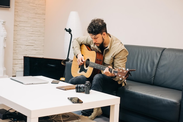 Joven tocando la guitarra en el sofá