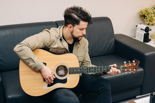 Joven tocando la guitarra en el sofá