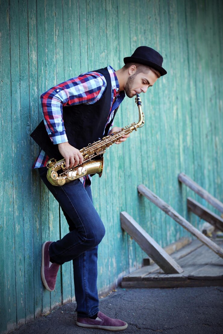 Foto joven tocando el saxofón fuera cerca de la antigua muralla