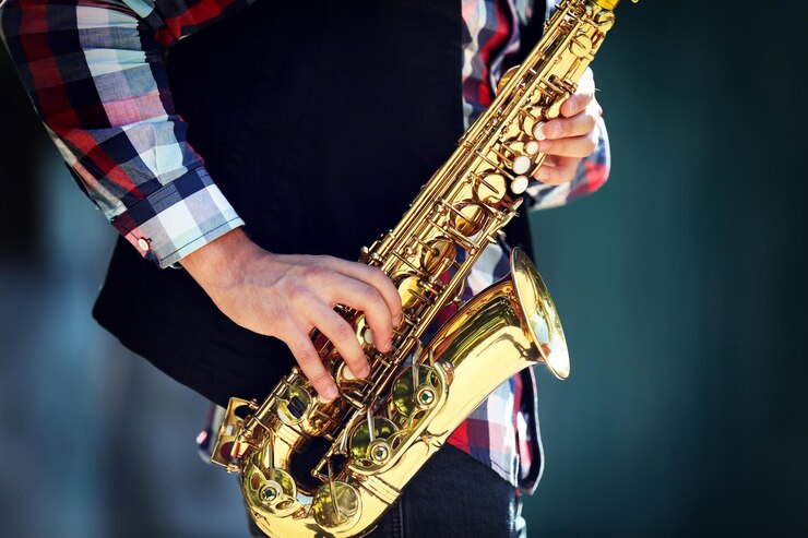 Foto joven tocando el saxofón fuera cerca de la antigua muralla