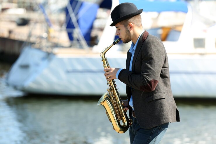 Foto joven tocando el saxofón en la orilla del río