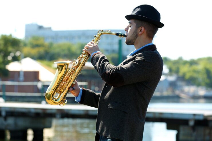 Foto joven tocando el saxofón en la orilla del río