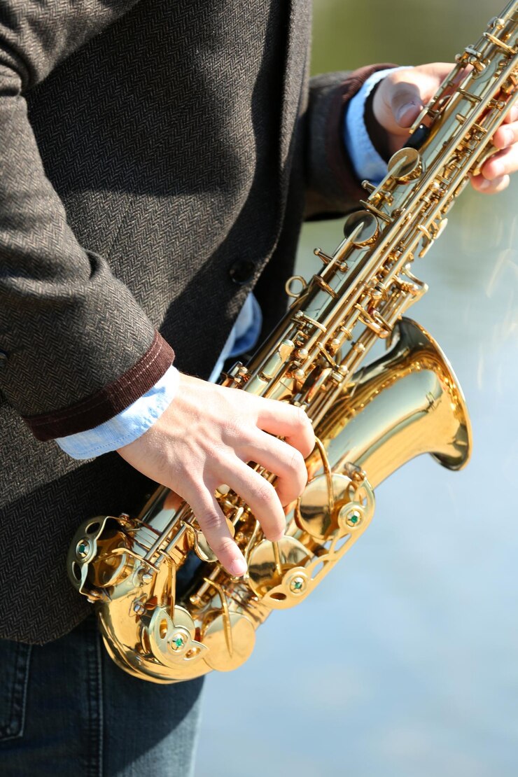 Foto joven tocando el saxofón en la orilla del río