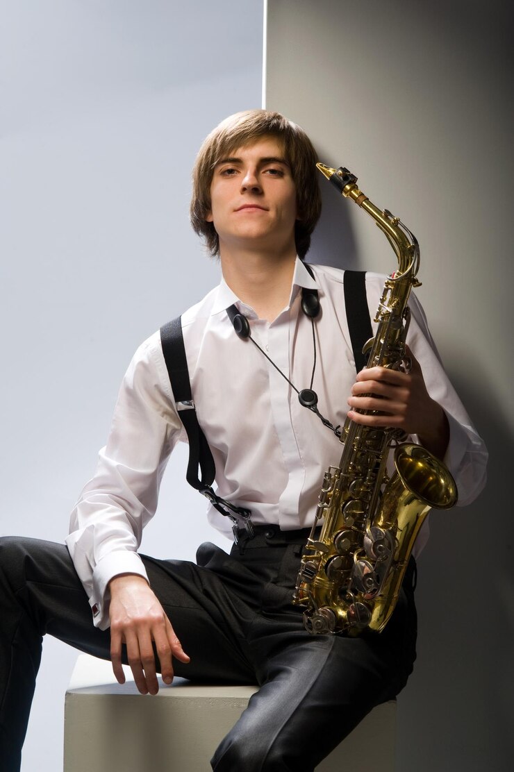 Foto joven tocando el saxofón sobre fondo blanco.