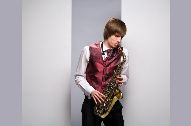 Foto joven tocando el saxofón sobre fondo blanco.