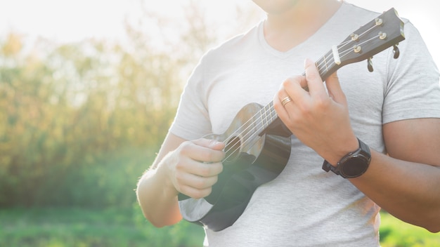 Joven tocando el ukelele en el parque