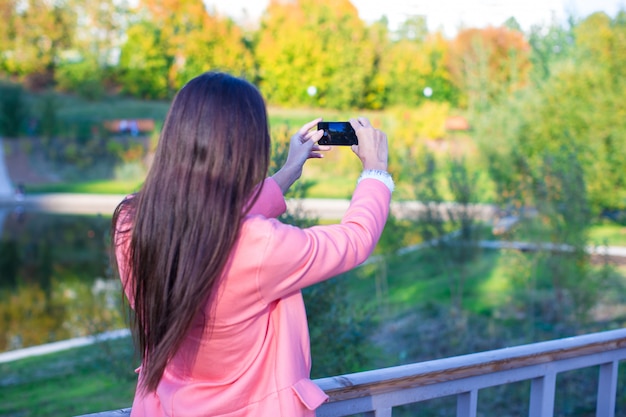 Joven toma una foto junto a su teléfono en el día de otoño