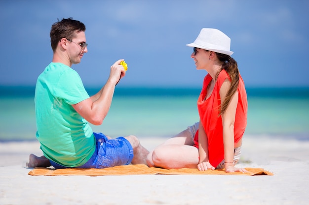 Joven toma una foto de su novia por teléfono en la playa