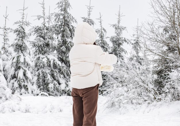 Una joven se toma una selfie en el bosque invernal