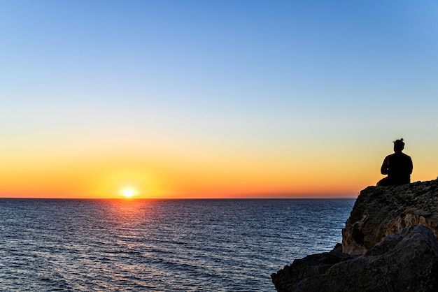 Joven tomando una cerveza viendo la puesta de sol en la playa de Barbate junto al faro de Trafalgar