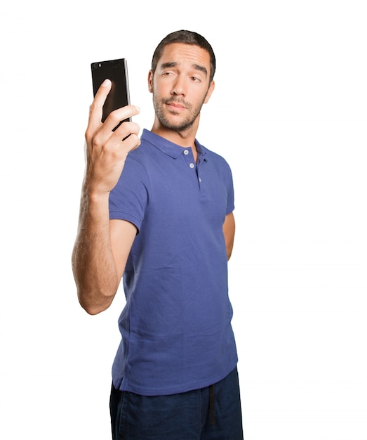 Joven tomando una foto con su teléfono móvil sobre fondo blanco