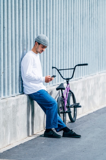 Foto joven tomando una foto con el teléfono inteligente con su bicicleta