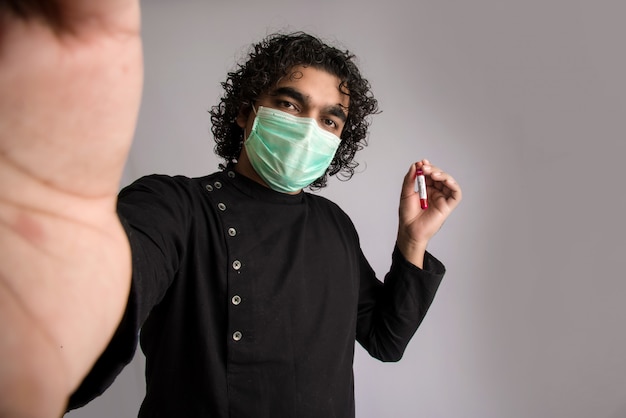 Joven tomando una selfie con un tubo de ensayo con muestra de sangre para coronavirus o análisis 2019-nCoV.