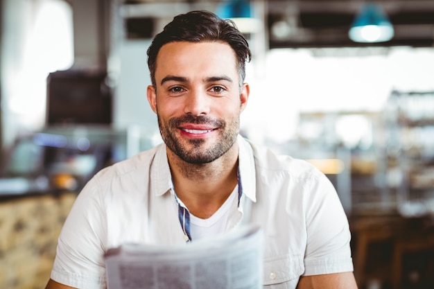 Foto joven tomando una taza de café leyendo periódico