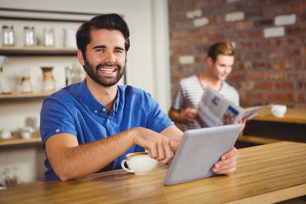 Joven tomando una taza de café con tableta