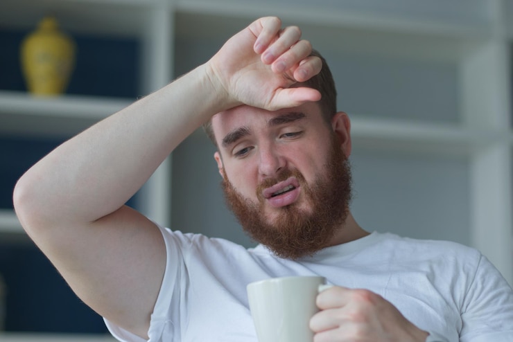 Foto joven tosiendo y sufriendo de bebida fría bebida caliente hombre sintiendo frío acostado en el sofá
