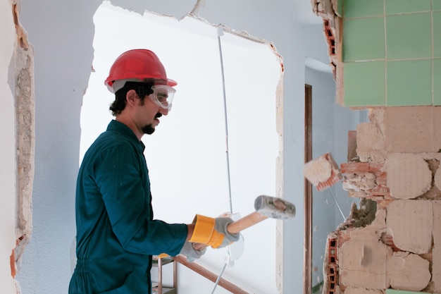 joven trabajador con un casco de protección rojo y vistiendo un traje de caldera azul. concepto de demolición