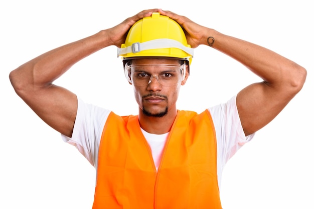 Joven trabajador de la construcción africana con ambas manos en el casco de seguridad