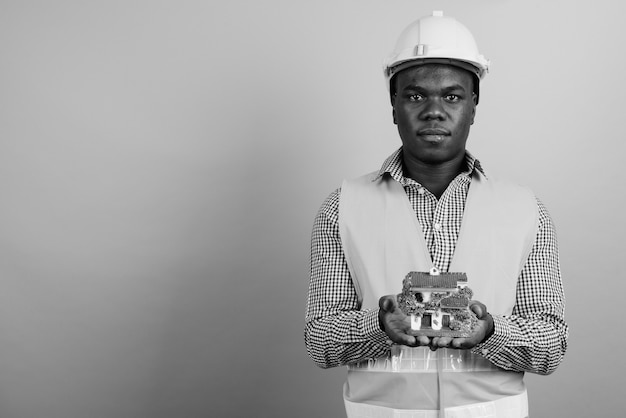 joven trabajador de la construcción africana contra la pared blanca. en blanco y negro