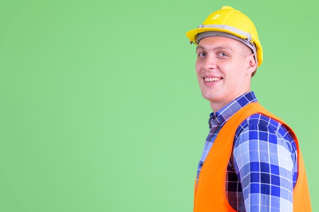 Joven trabajador de la construcción contra la pared verde