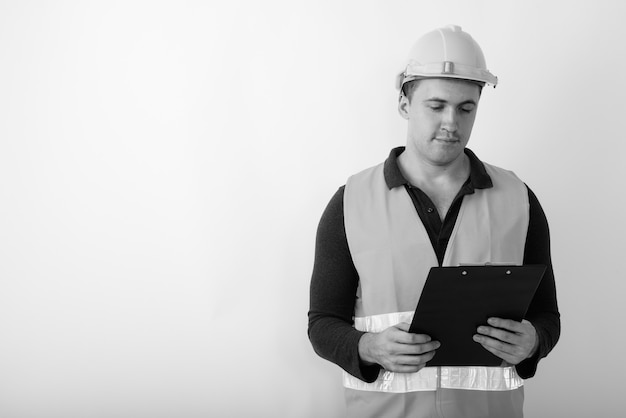 joven trabajador de la construcción musculoso leyendo en el portapapeles.