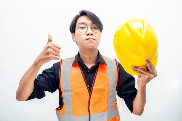 Joven trabajador de la construcción o ingeniero asiático sonriendo felizmente y dando pulgares hacia arriba como cumplido.