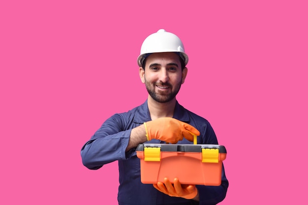 Joven trabajador de la construcción sonriendo y sosteniendo la caja de herramientas modelo paquistaní indio