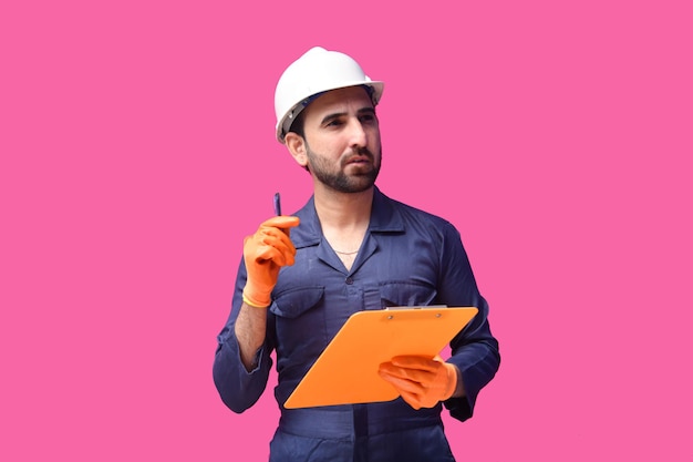 Joven trabajador de la construcción sonriendo y sosteniendo la pluma con el portapapeles modelo paquistaní indio