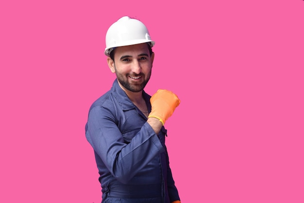 Joven trabajador de la construcción vistiendo camisa azul posando sobre fondo rosa modelo paquistaní indio