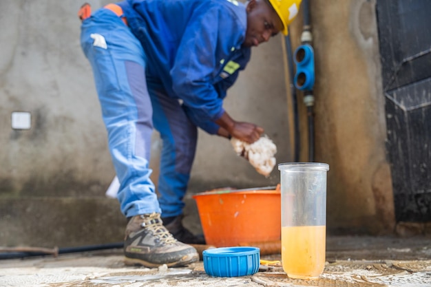 Joven trabajador de cuello azul africano lavando los contenedores de filtros Concepto de filtración de agua