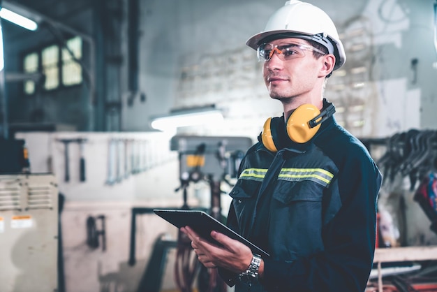 Joven trabajador de fábrica que usa una tableta experta en un edificio de taller