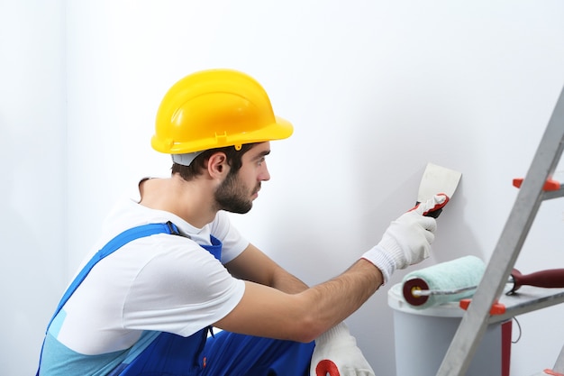 Joven trabajador haciendo reparaciones en la habitación